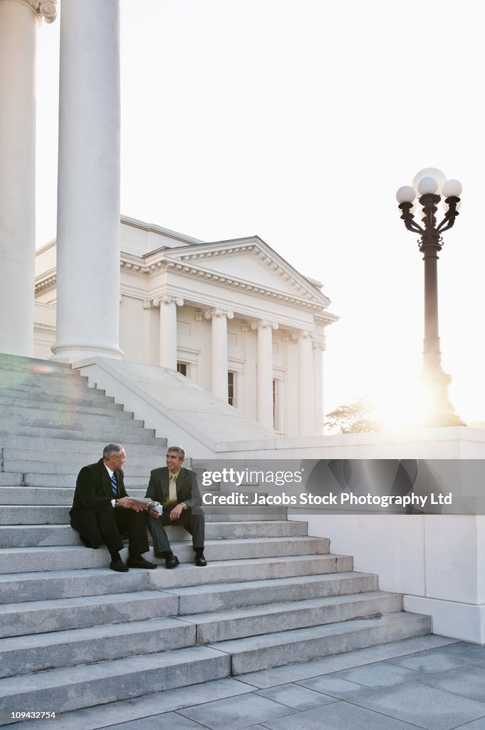 Businessman sitting on steps talking