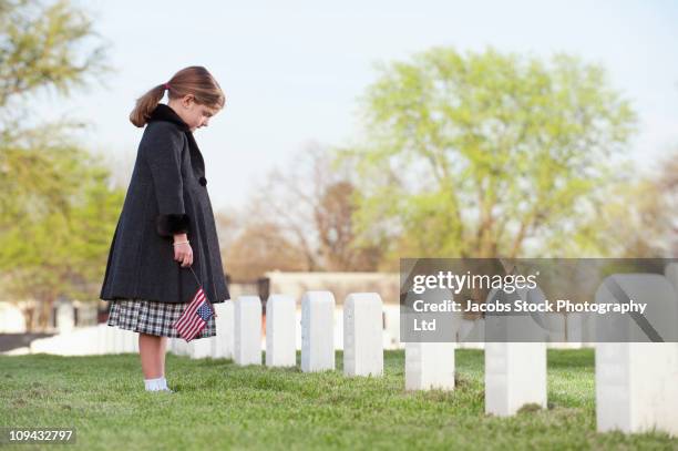 niña caucásica con bandera estadounidense visite el cementerio - war memorial holiday fotografías e imágenes de stock