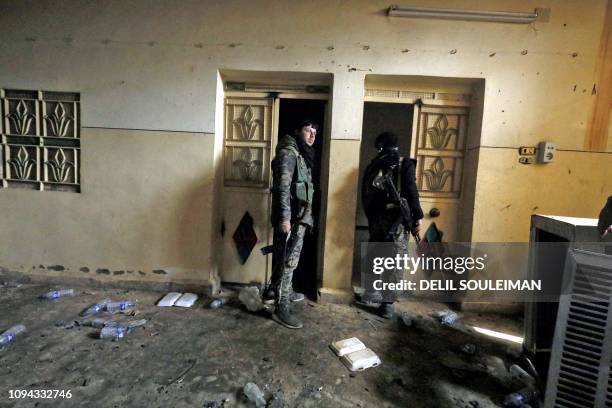 Fighter from the Syrian Democratic Forces walk inside a former Islamic State group prison in the city of Hajin in Syria's eastern Deir Ezzor province...