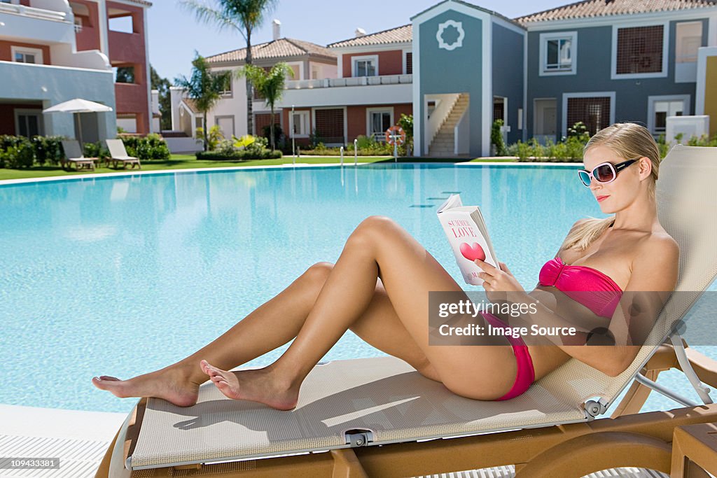 Woman reading book on sunlounger on vacation