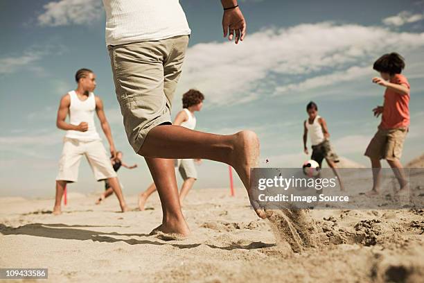 jungs spielen fußball am strand - hispanic man on beach stock-fotos und bilder