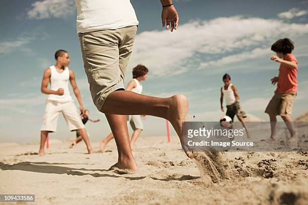 boys playing football on beach - latina legs stockfoto's en -beelden