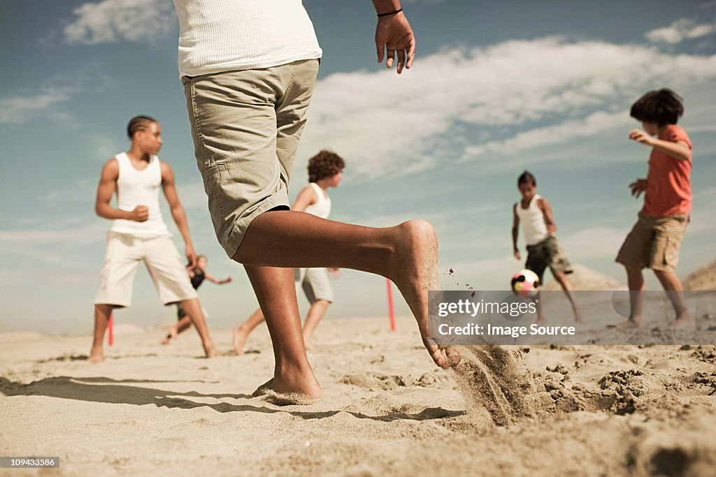 Boys playing football on beach