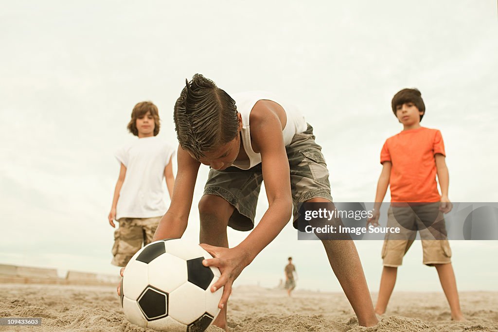 Boys playing football on beach