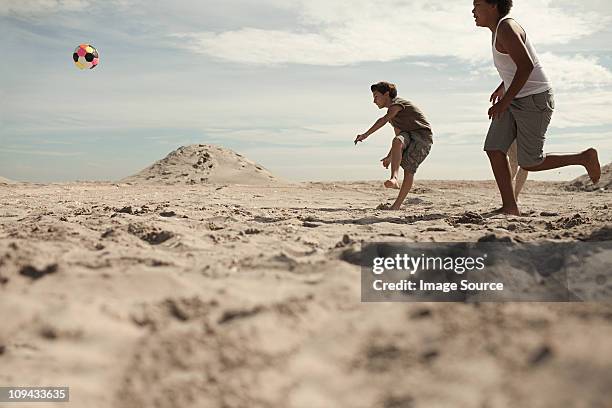 jungs spielen fußball am strand - fußball 2 jungs stock-fotos und bilder