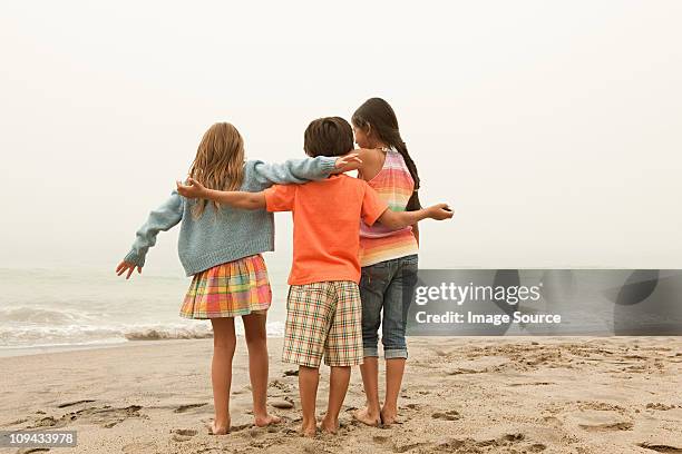 three children on beach - sibling hugging stock pictures, royalty-free photos & images