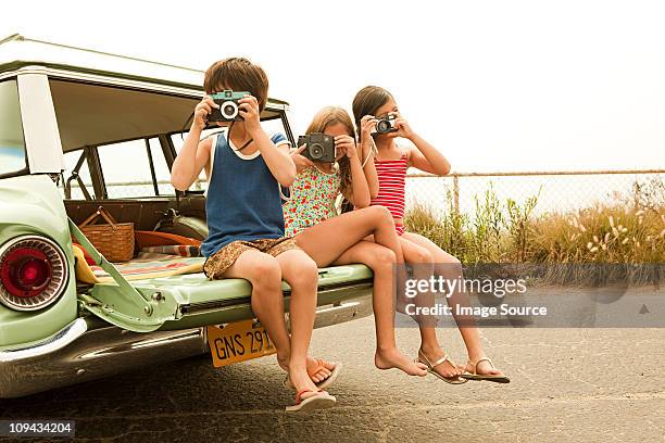 three children sitting on back of estate car taking photographs - photographing bildbanksfoton och bilder