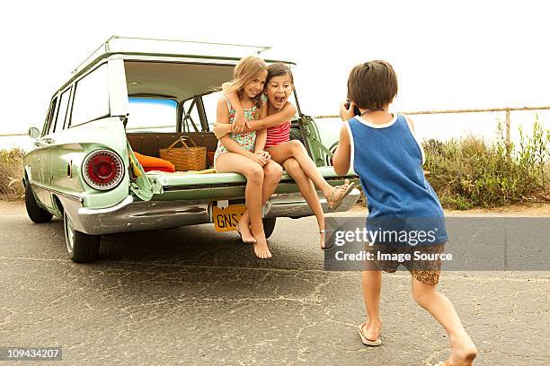 three children sitting on back of estate car taking photographs - station wagon stock pictures, royalty-free photos & images