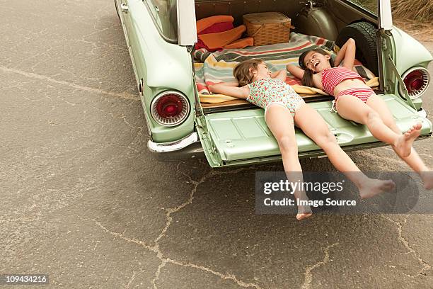 deux filles allongé en voiture de la propriété - fille maillot photos et images de collection