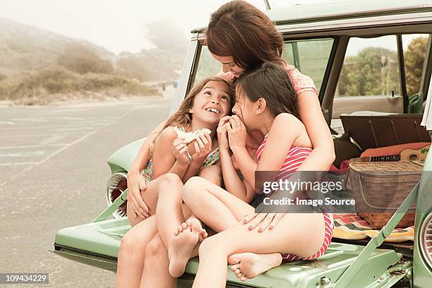 mother and daughters eating sandwiches on car boot - 1950s california stockfoto's en -beelden