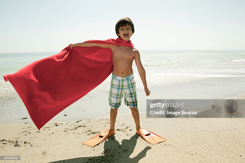 Junge mit Schwimmflossen und red cape am Strand