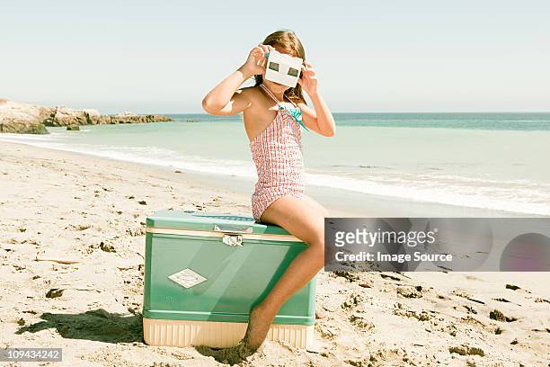 mädchen sitzt auf coolbox am strand schaut durch folie betrachter - kühlbehälter stock-fotos und bilder