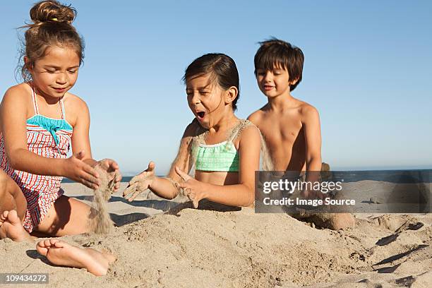niños enterrando chica en la arena - bury fotografías e imágenes de stock