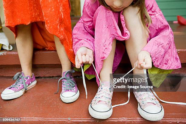 two girls, one tying up shoelace - amarrar o cadarço - fotografias e filmes do acervo