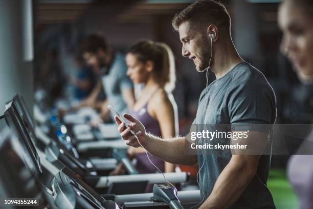 gärna manliga idrottare lyssnar musik på löpband i ett gym. - gym bildbanksfoton och bilder