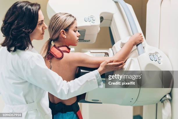 jeune femme ayant un balayage du sein - équipement de radiologie photos et images de collection