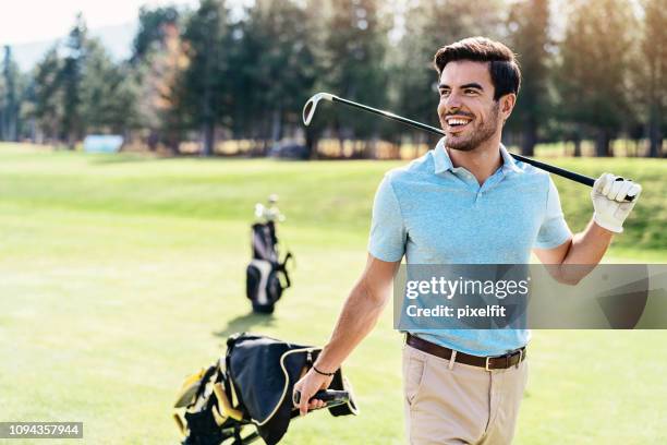 smiling golf player walking and pulling his golf bag - male golfer stock pictures, royalty-free photos & images