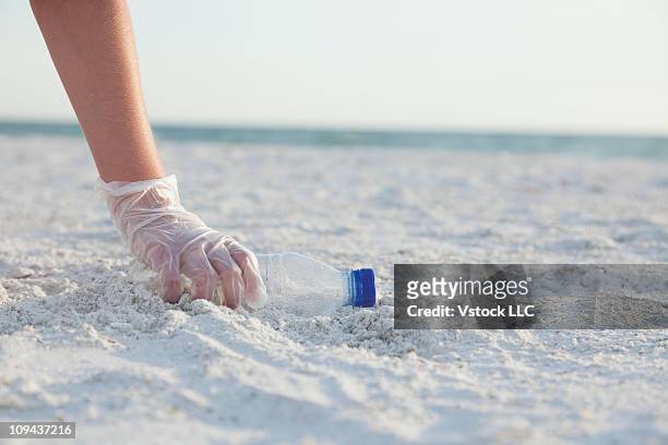 usa, florida, st. petersburg, girl (10-11) collecting plastic bottle on beach - kids with cleaning rubber gloves 個照片及圖片檔