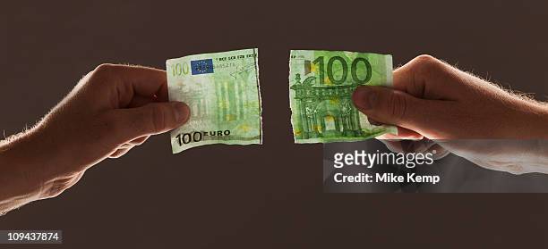 hands holding torn one hundred euro note - one hundred euro note stock pictures, royalty-free photos & images