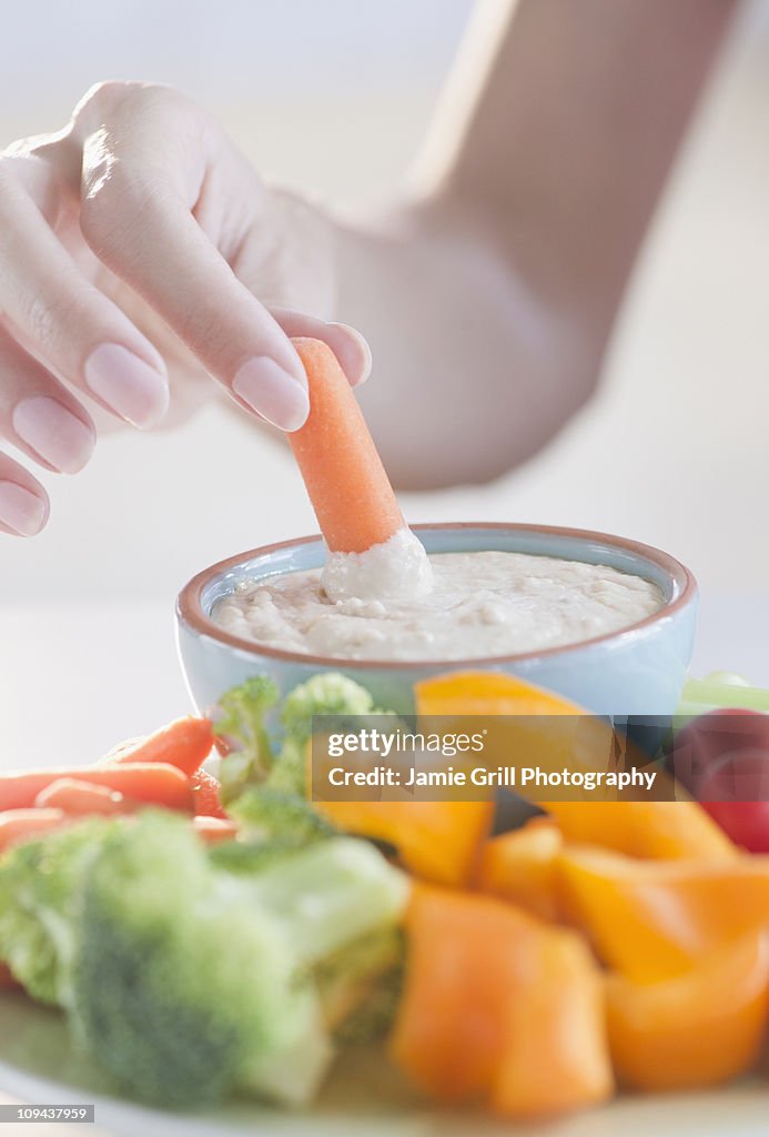 USA, New Jersey, Jersey City, Close-up view of woman hand putting baby carrot into dip