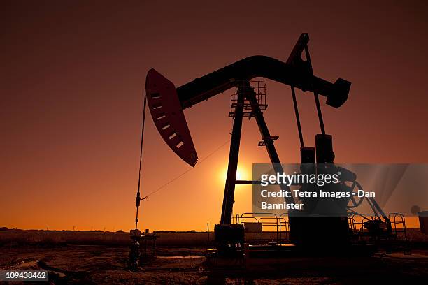 silhouette of oil pump jack on rig - oil rig stock pictures, royalty-free photos & images