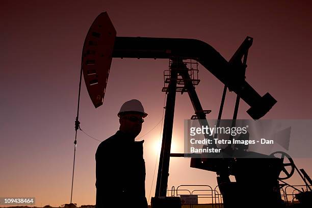 silhouette of oil worker by pump jack on rig - oil pump stock pictures, royalty-free photos & images