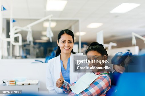 Female dentist and girl patient smiling at camera Female dentist and girl patient smiling at camera