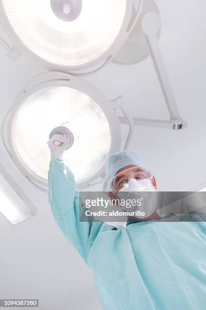 vista de ángulo bajo de médico sosteniendo la lámpara y mirando hacia abajo - flu mask in mexico fotografías e imágenes de stock