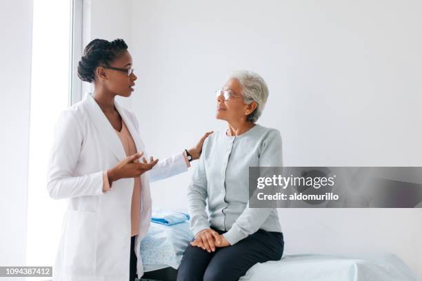 doctora, de pie junto al paciente altos y hablar con ella - haitian ethnicity fotografías e imágenes de stock