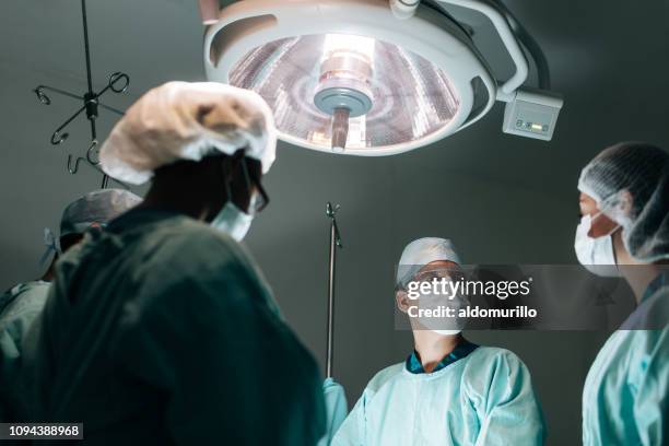 vista de ángulo bajo de trabajadores de la salud durante la cirugía - flu mask in mexico fotografías e imágenes de stock