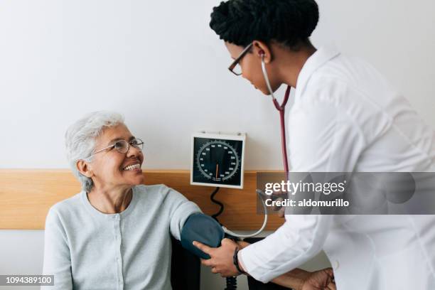 female doctor checking blood pressure to senior patient - high blood pressure stock pictures, royalty-free photos & images