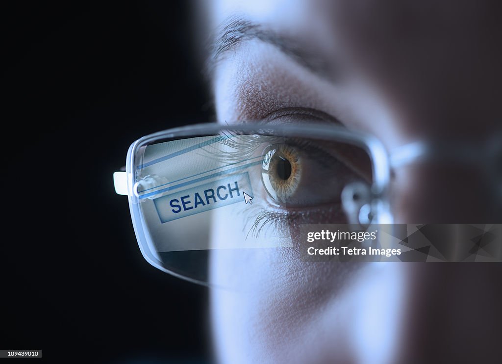 Reflection of search button in businesswoman's glasses