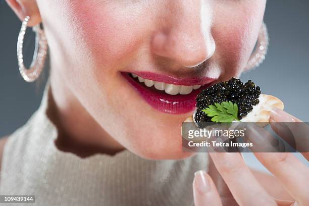 young woman eating caviar on biscuit - fish roe stock pictures, royalty-free photos & images
