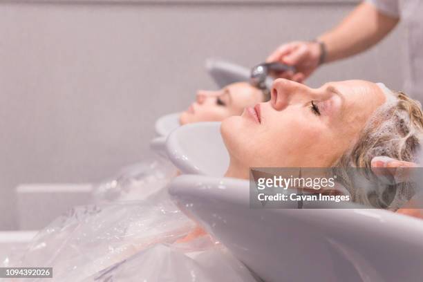 cropped hands of male hairdressers washing customers hair in salon - sud side company stock pictures, royalty-free photos & images