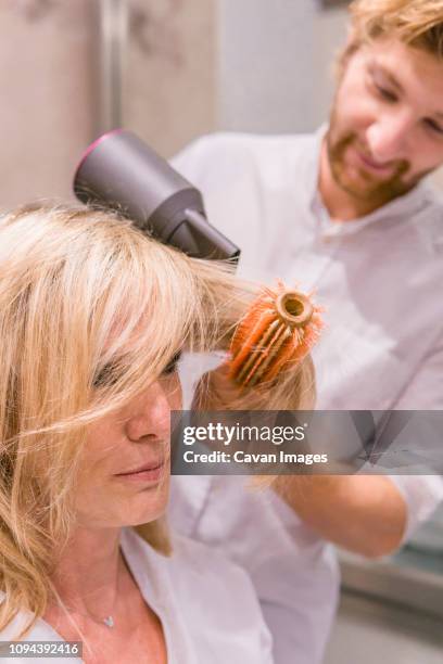 hairdresser drying female customer's hair in salon - older woman wet hair stock pictures, royalty-free photos & images