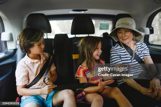 smiling grandmother with grandchildren traveling in taxi - taxi boys stock pictures, royalty-free photos & images