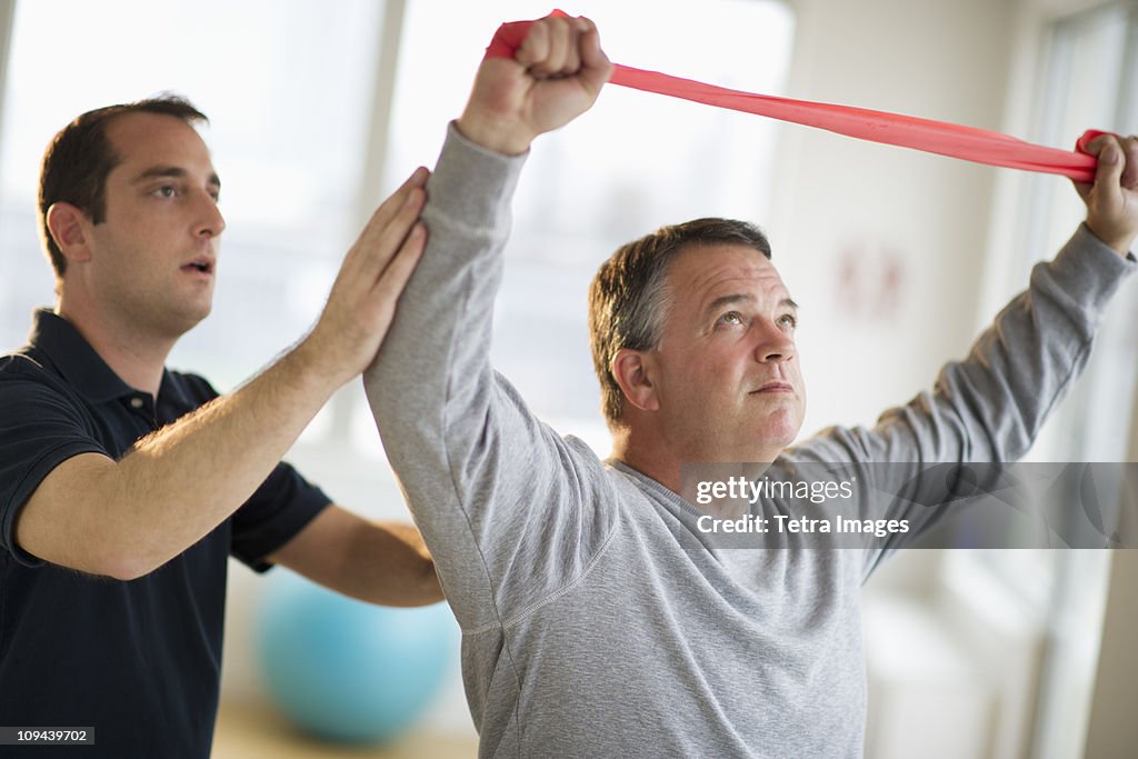 USA, New Jersey, Jersey City, Fitness instructor assisting man in gym