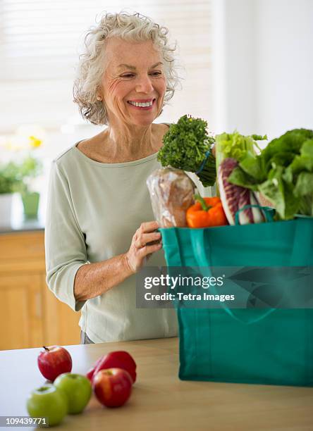 usa, new jersey, jersey city, senior woman with grocery bag in kitchen - jersey city stock pictures, royalty-free photos & images