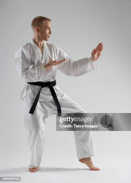 young man performing karate stance on white background - karate stockfoto's en -beelden
