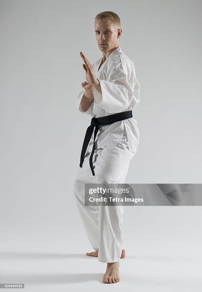 Young man performing karate stance on white background