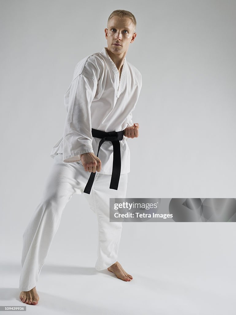 Young man performing karate stance on white background