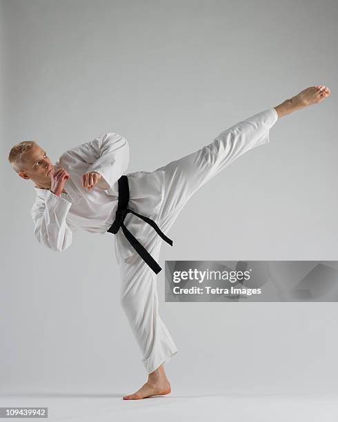 young man performing karate kick on white background - martial arts background stock pictures, royalty-free photos & images