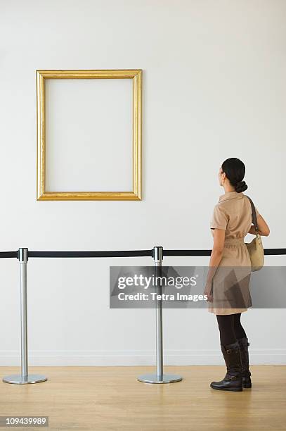 woman looking at blank picture frame in art gallery - white purse stock-fotos und bilder