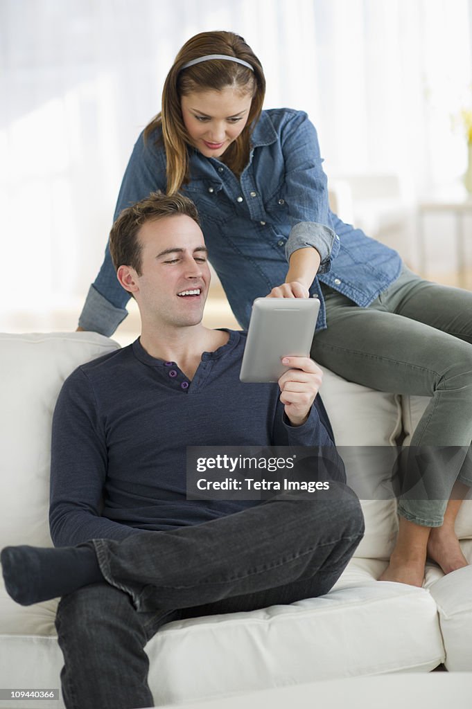 USA, New Jersey, Jersey City, Portrait of young couple sitting on sofa with digital tablet