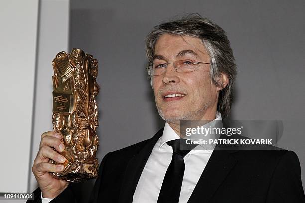 French set designer Hugues Tissandier poses with his trophy during a photocall after winning the Best Production Designer award for French director...