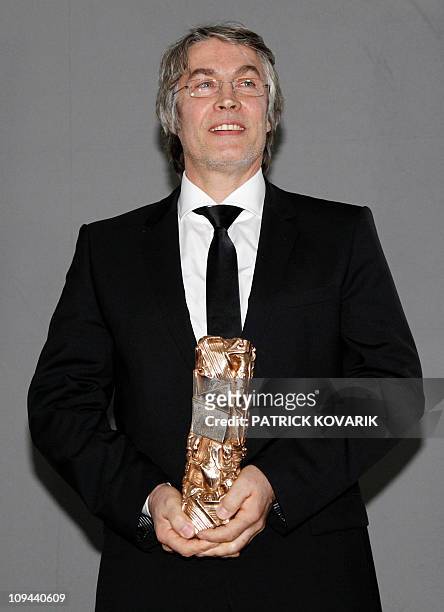 French set designer Hugues Tissandier poses with his trophy during a photocall after winning the Best Production Designer award for French director...