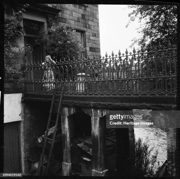 Ireland Bridge, Bingley, Bradford, West Yorkshire, 1966-1974. A woman standing on the footbridge linking the house at 6 Ireland Bridge to the...