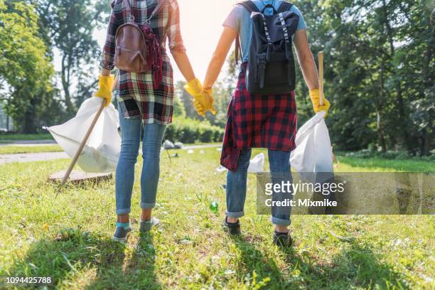 couple cleaning the local park together - picking up garbage stock pictures, royalty-free photos & images
