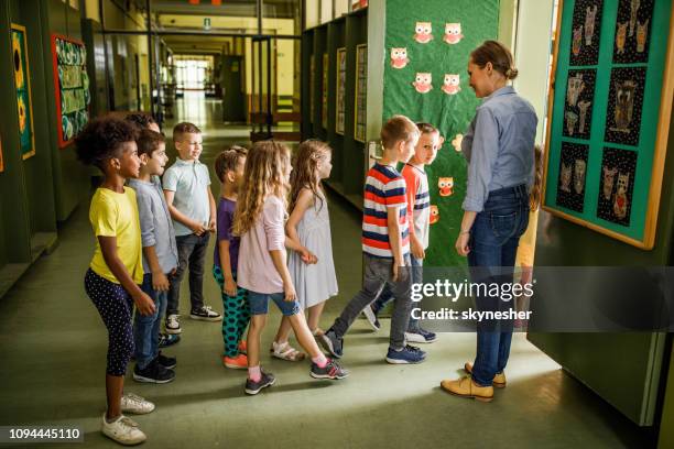 gelukkig vrouwelijke leraar verwelkomen elementaire studenten in de klas. - schoolboy stockfoto's en -beelden