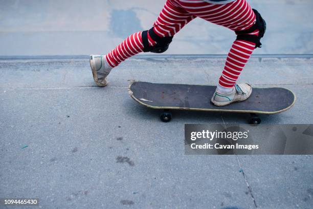 low section of boy skateboarding on sports ramp at skateboard park - knieschützer stock-fotos und bilder